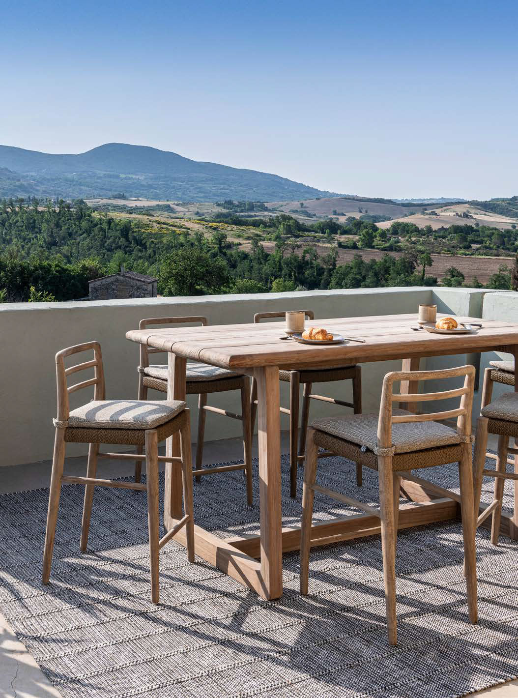 Outdoor Barstuhl Jared aus naturbelassenem Teakholz mit PE-Wicker-Geflecht auf der Sitzfläche, perfekt für Terrassen und Außenbereiche.