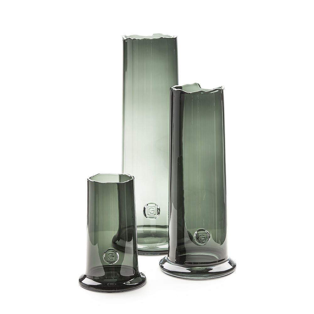 Gommaire Vase Nikky in den Größen Small, Medium und Large aus mundgeblasenem grauen Glas, gefüllt mit grünen Zweigen. Stilvolle Vasen im modernen Design.