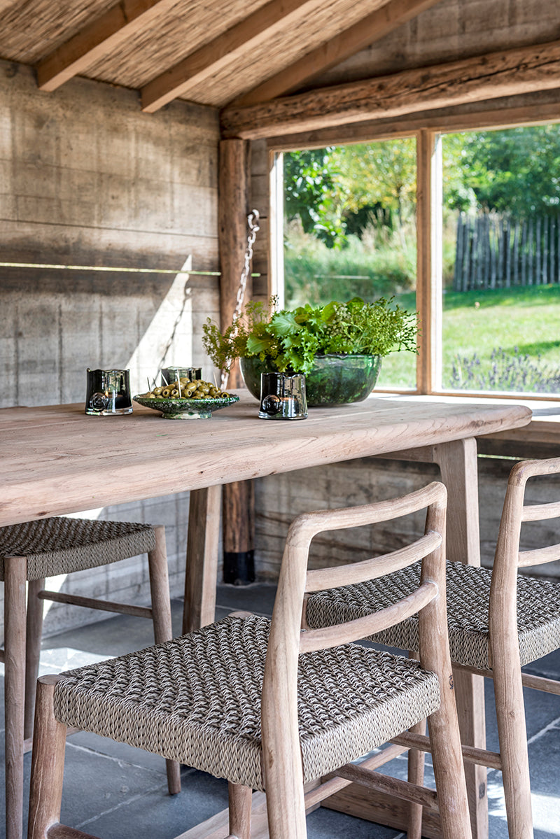 Outdoor Barstuhl Jared aus naturbelassenem Teakholz mit PE-Wicker-Geflecht auf der Sitzfläche, perfekt für Terrassen und Außenbereiche.