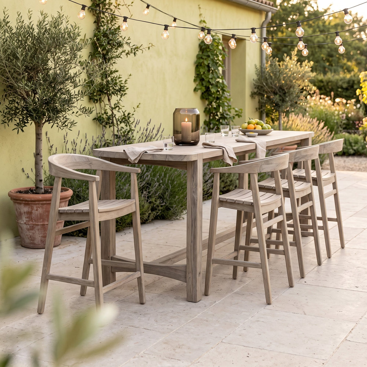 Barstuhl Faye Teak Natural Grey von Gommaire, Teak Natural Grey, B 54 × T 51 × H 94 cm, am Bartisch Jacoba mit Windlicht Daniel auf der Barterrasse