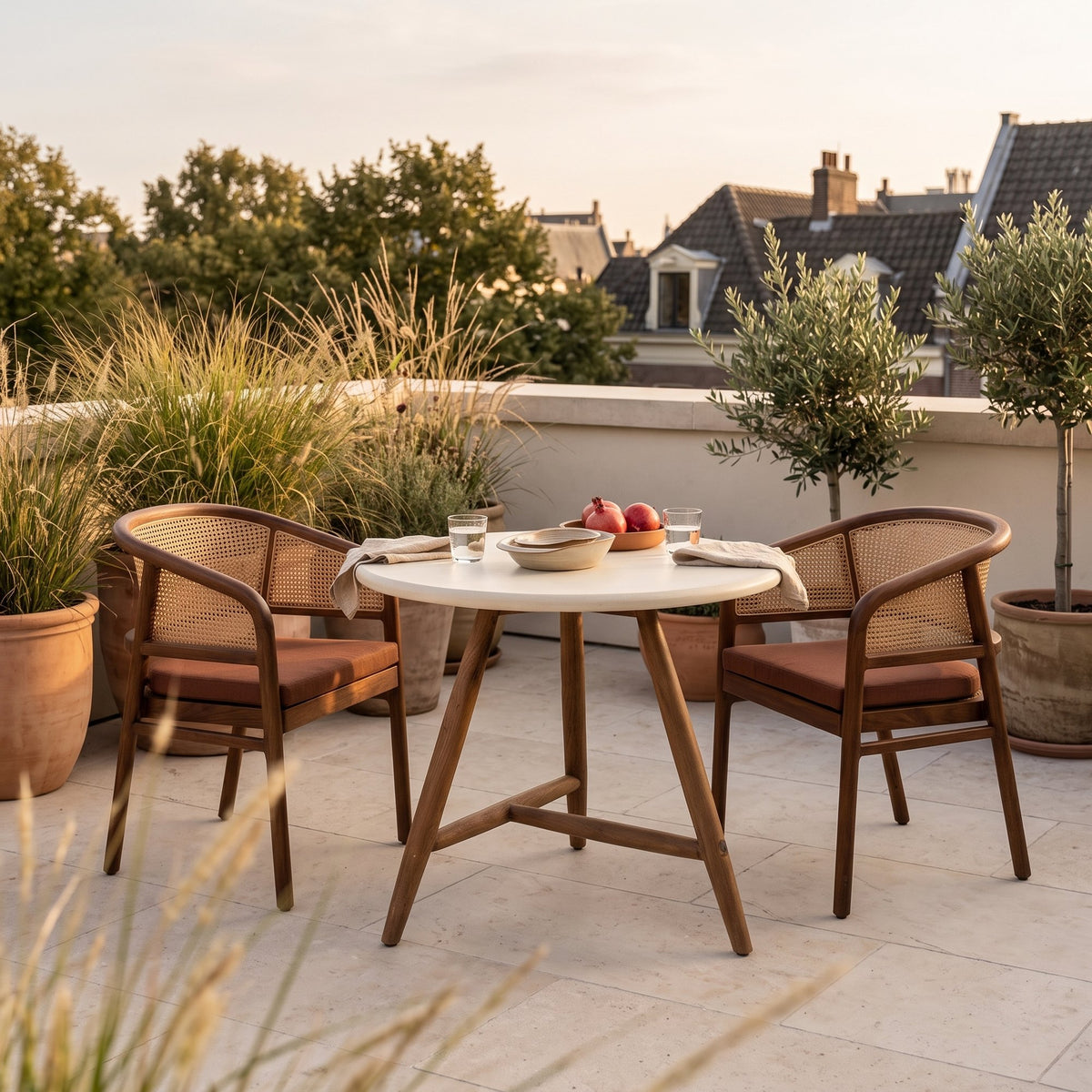 Bistrotisch Faye rund Beton Teak Emas Brown von Gommaire, Beton und Teak Emas Brown, Ø 75 × H 76 cm, Ambiente mit Armlehnenstühlen Imen und Schale Ali auf der Dachterrasse
