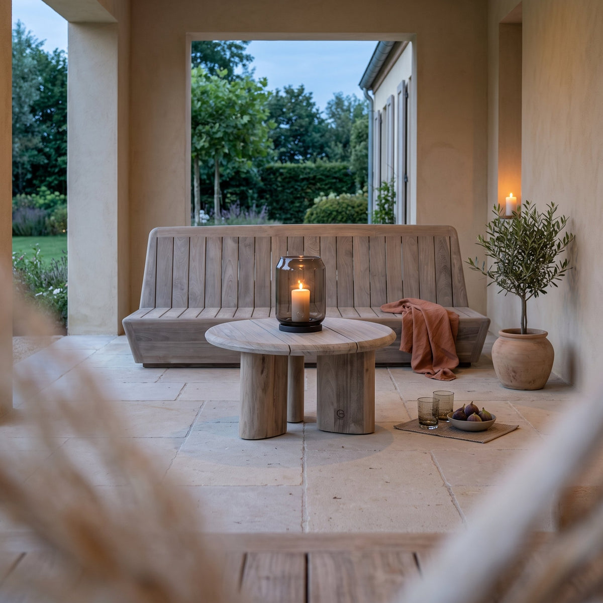 Couchtisch Imen rund Teak Natural Grey Small von Gommaire, Teak Natural Grey, Ø 65 × H 35 cm, vor dem Outdoor Sofa Jules mit Windlicht Daniel in der Loggia