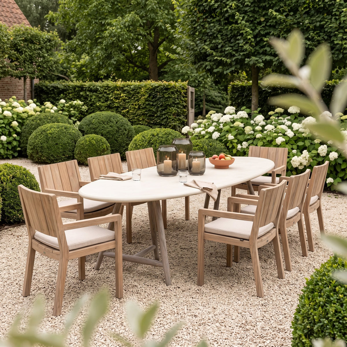 Esstisch Faye oval Beton Teak Natural Grey von Gommaire, Beton und Teak Natural Grey, 250 × 105 × H 76 cm, Ambiente mit Armlehnenstühlen Mario und Windlicht Daniel im Kiesgarten