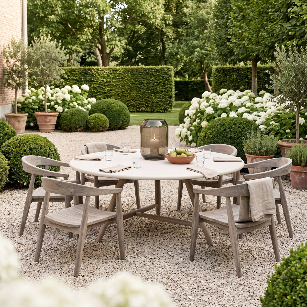 Esstisch Faye rund Beton Teak Natural Grey XL Low von Gommaire, Beton und Teak Natural Grey, Ø 170 × H 69 cm, Interiorbild mit Sesseln Faye und Windlicht Daniel im Kiesgarten