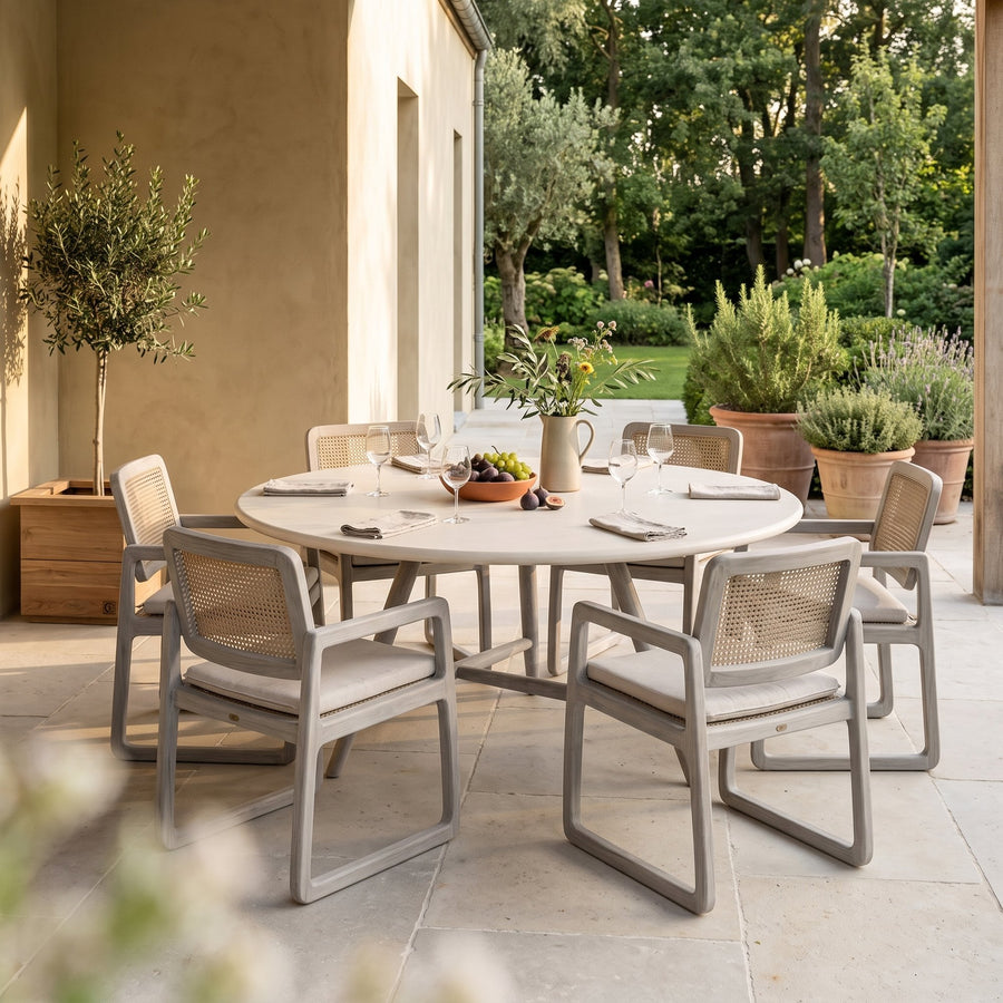 Esstisch Faye rund Beton Teak Natural Grey XL Low von Gommaire, Beton und Teak Natural Grey, Ø 170 × H 69 cm, Ambiente mit Loungesesseln Sally Open Weave und Pflanzkübel Ferdy auf der Gartenterrasse
