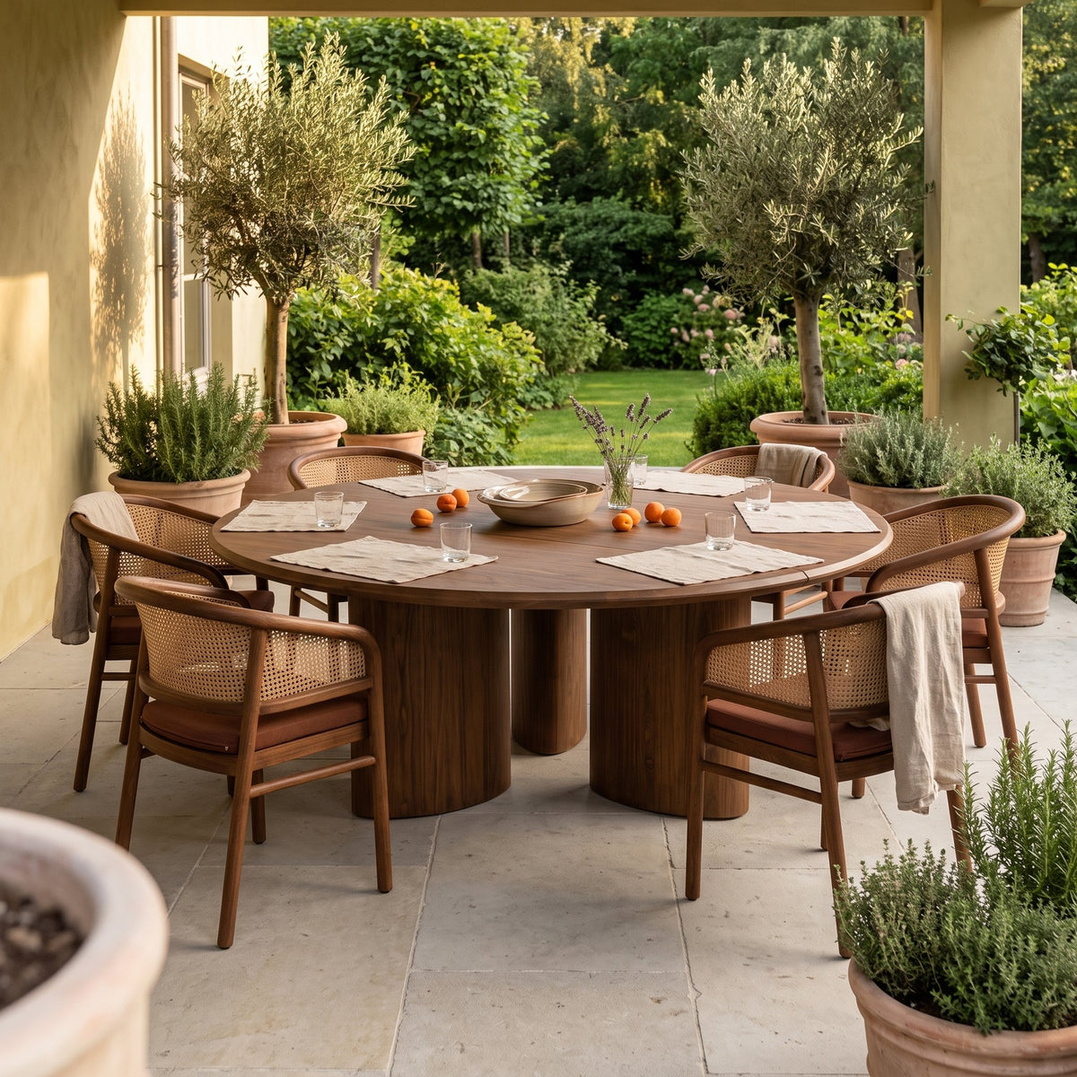 Esstisch Imen rund Teak Emas Brown von Gommaire, Teak Emas Brown, Ø 200 × H 76 cm, mit Armlehnenstühlen Imen und Schale Ali auf der Gartenterrasse