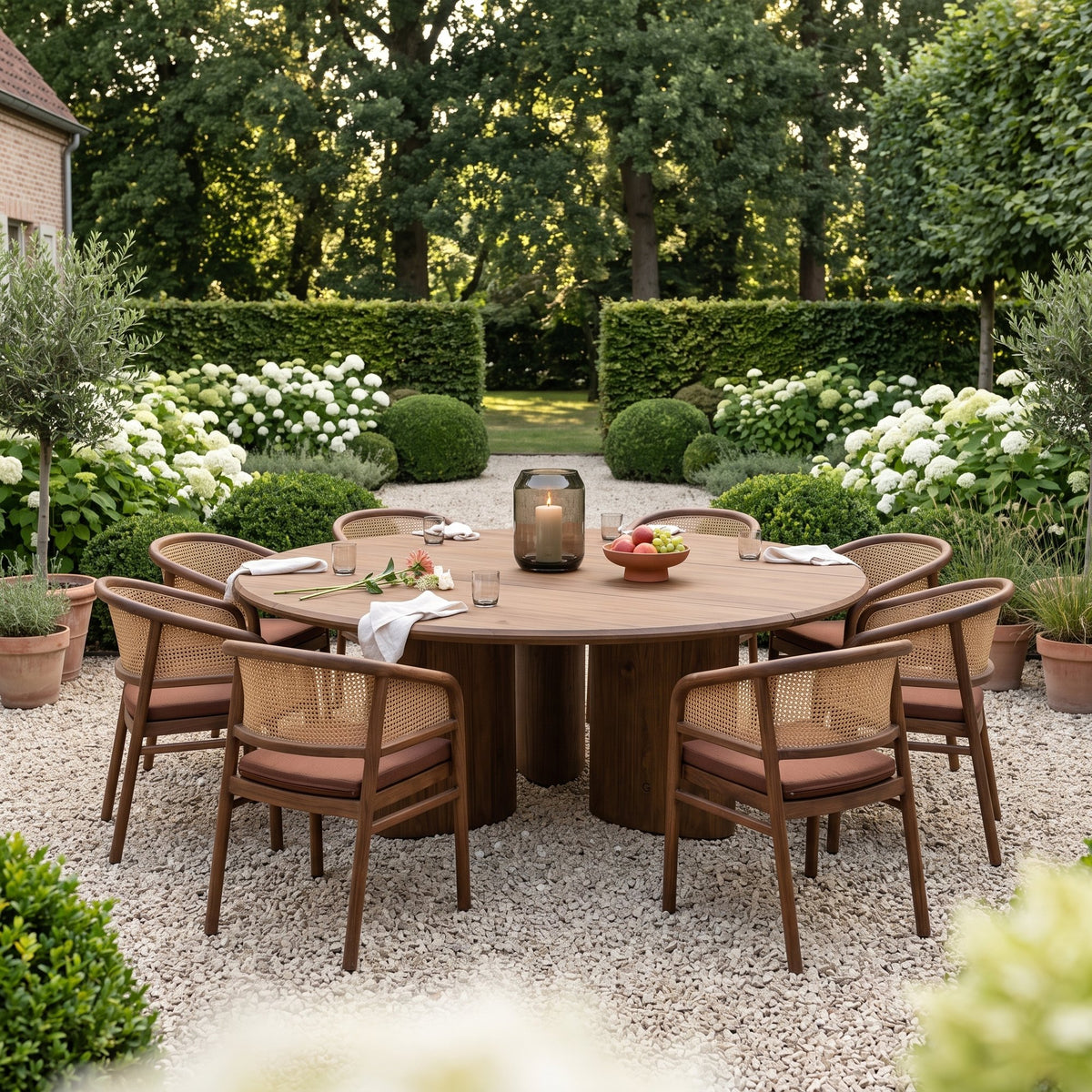 Esstisch Imen rund Teak Emas Brown von Gommaire, Teak Emas Brown, Ø 200 × H 76 cm, mit Armlehnenstühlen Imen und Windlicht Daniel im Kiesgarten