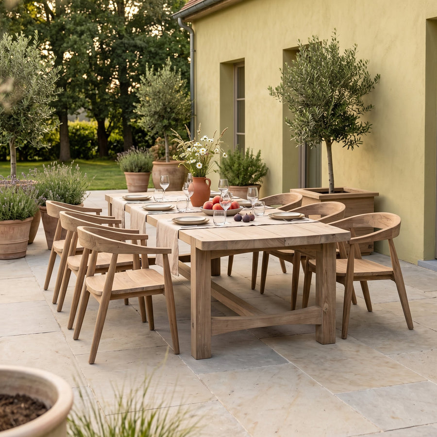 Esstisch Jacoba Small Teak Natural Grey Low von Gommaire, Teak Natural Grey, 270 × 102 × H 69 cm, Ambiente mit Sesseln Faye und Pflanzkübel Ferdy auf der Gartenterrasse