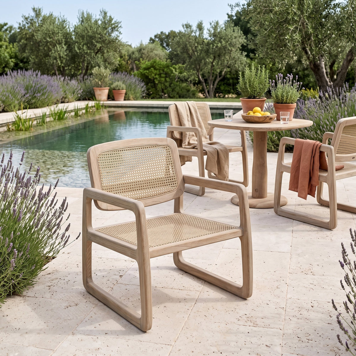 Loungesessel Sally Open Weave Teak Natural Grey von Gommaire, Teak Natural Grey und PE-Rattan, B 67 × T 75 × H 78,5 cm, im Vordergrund, dahinter Armlehnstühle Sally am Bistrotisch Dita am Pool