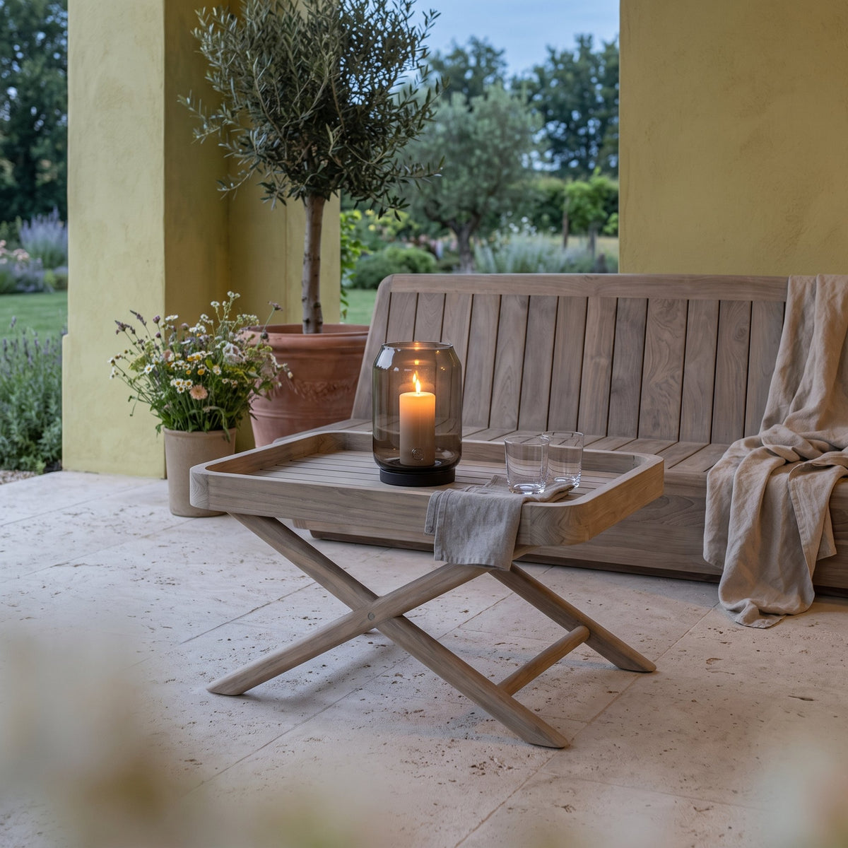 Tabletttisch James Teak Natural Grey Small von Gommaire, Teak Natural Grey, 55 × 35 × H 40 cm, vor dem Outdoor Sofa Jules mit Windlicht Daniel in der Loggia