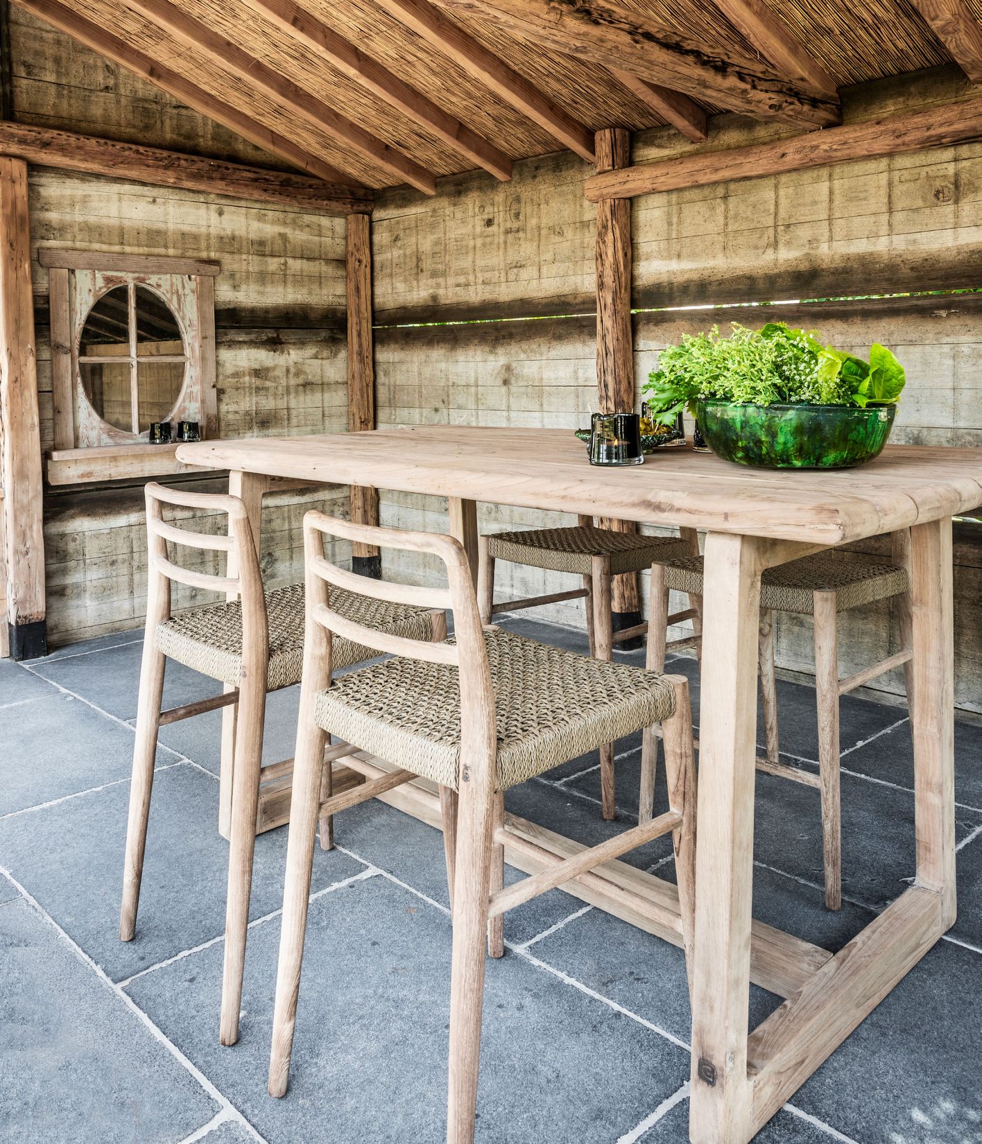 Outdoor Barstuhl Jared aus naturbelassenem Teakholz mit PE-Wicker-Geflecht auf der Sitzfläche, perfekt für Terrassen und Außenbereiche.