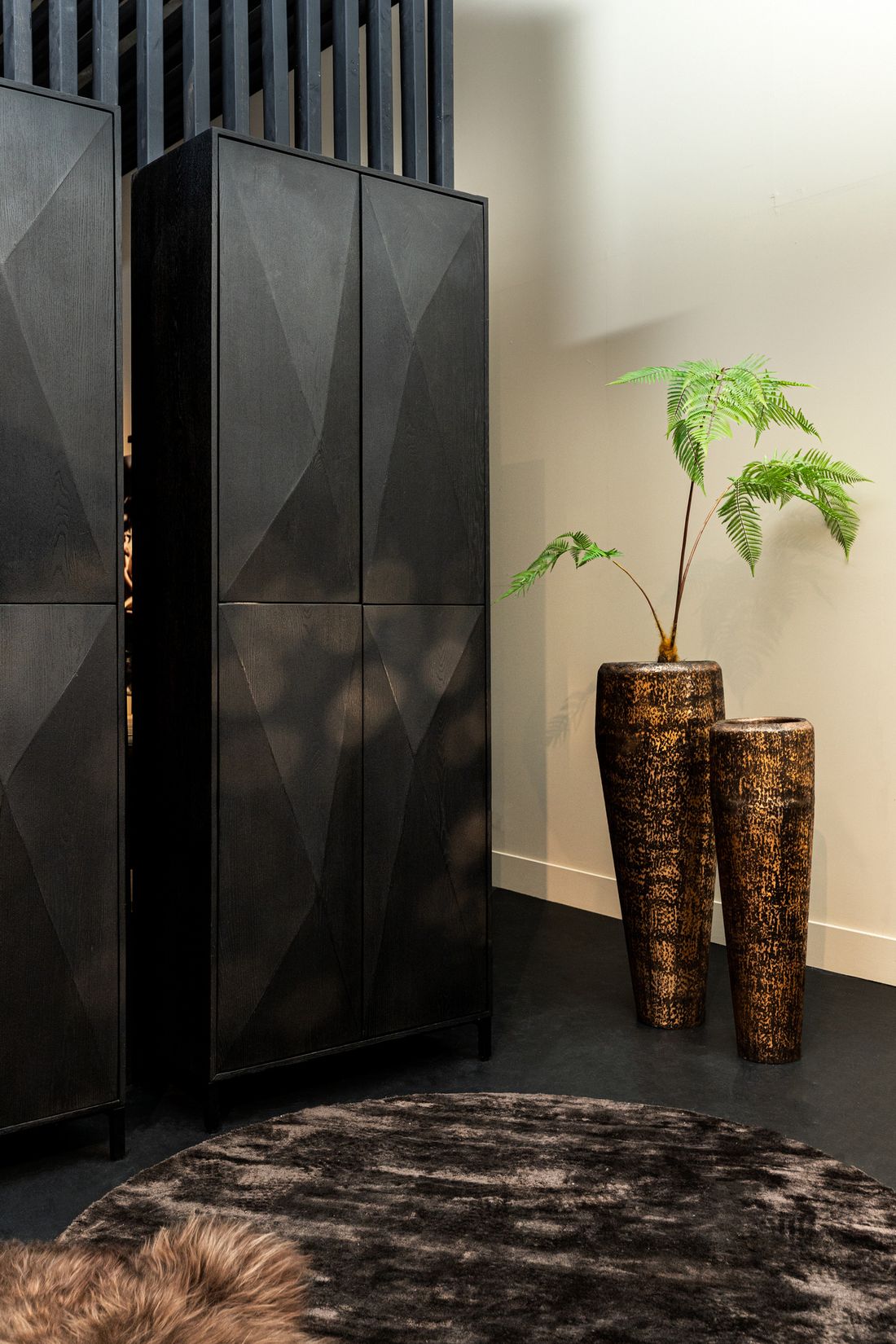 Onyx 4-Türiger Hochschrank in edlem Schwarz, präsentiert neben einem stilvollen Interieur mit Pflanzendekoration