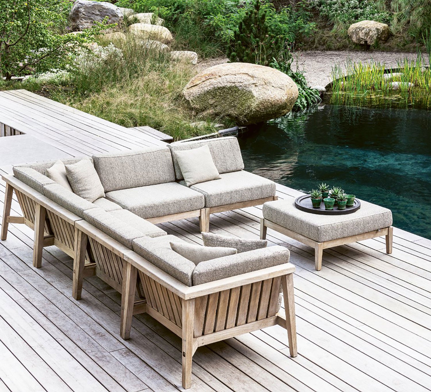 Modulares Copenhagen Outdoor-Loungesystem aus massivem Teakholz mit verschiedenen Sofaelementen und Polstern in Natural Grey auf großer Terrasse | STUFF Shop