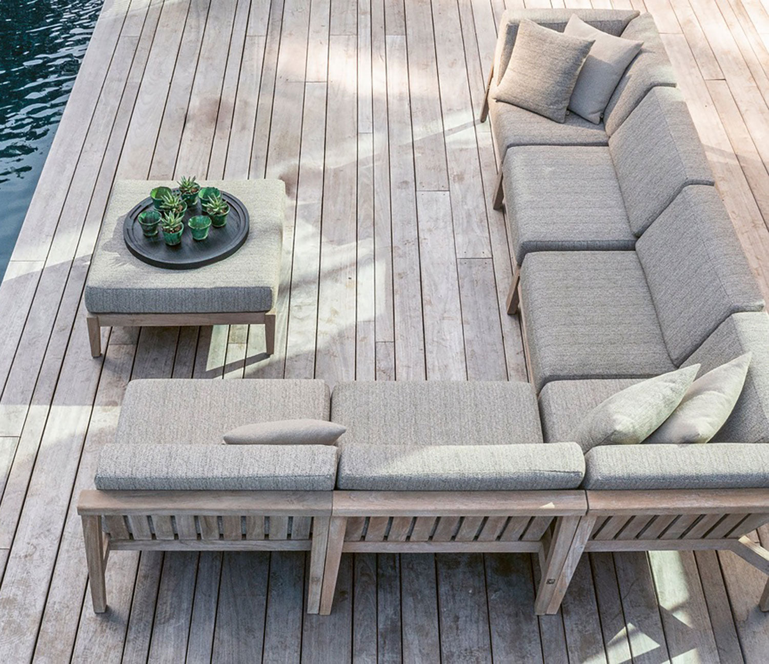 Modulares Copenhagen Outdoor-Loungesystem aus massivem Teakholz mit verschiedenen Sofaelementen und Polstern in Natural Grey auf großer Terrasse | STUFF Shop