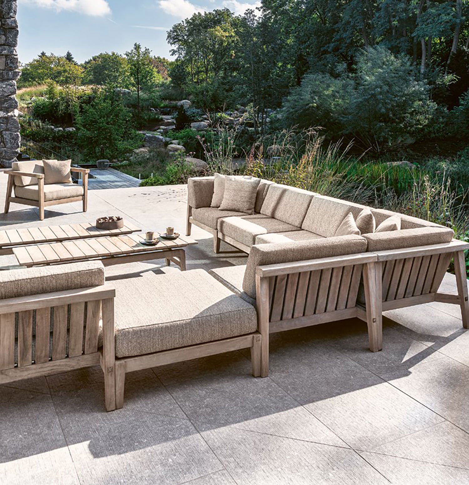 Modulares Copenhagen Outdoor-Loungesystem aus massivem Teakholz mit verschiedenen Sofaelementen und Polstern in Natural Grey auf großer Terrasse | STUFF Shop