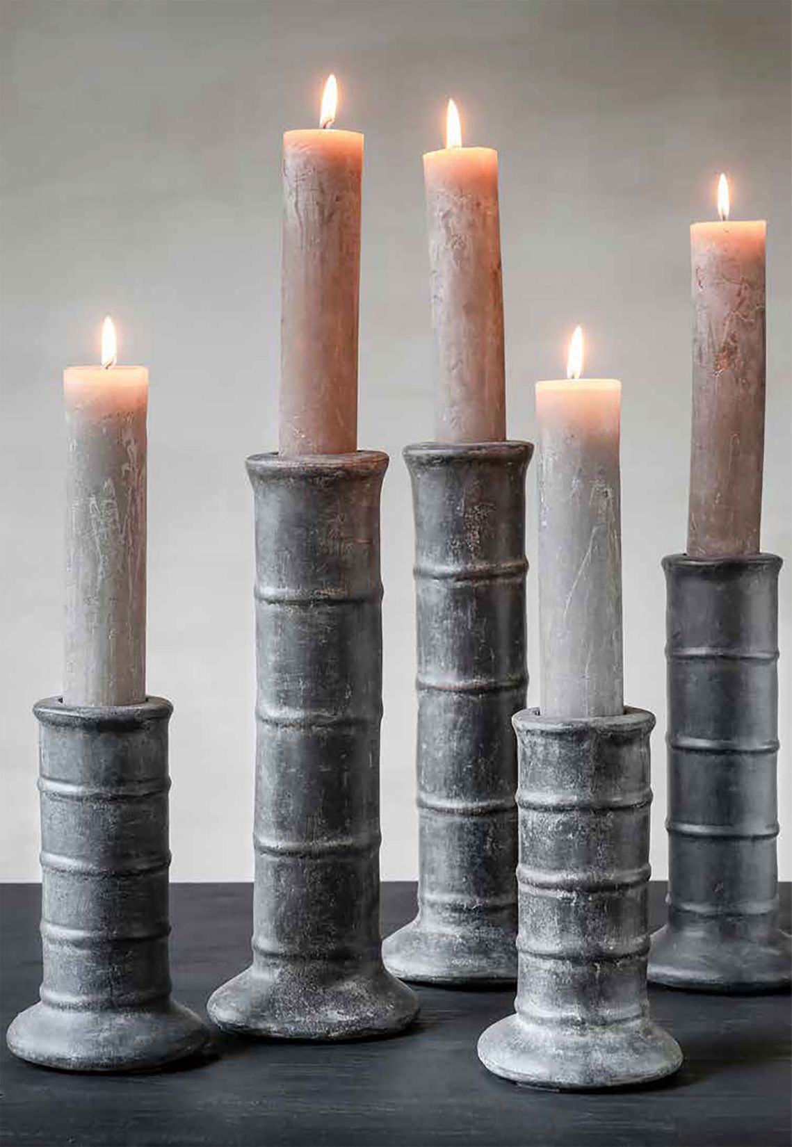 Gommaire 3-Set Kerzenständer "TERRACOTTA FUME PATINE" in abgestuften Höhen mit rauchigem Finish auf einem Tisch.