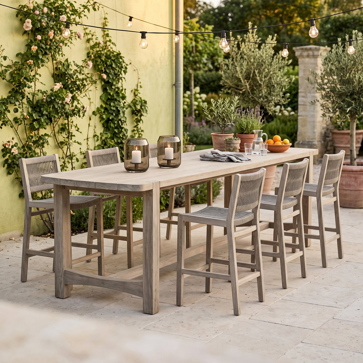 Bartisch Jacoba Teak Natural Grey von Gommaire, Teak Natural Grey, 300 × 97 × H 95 cm, mit Barstühlen Mario und Windlicht Daniel auf der Barterrasse