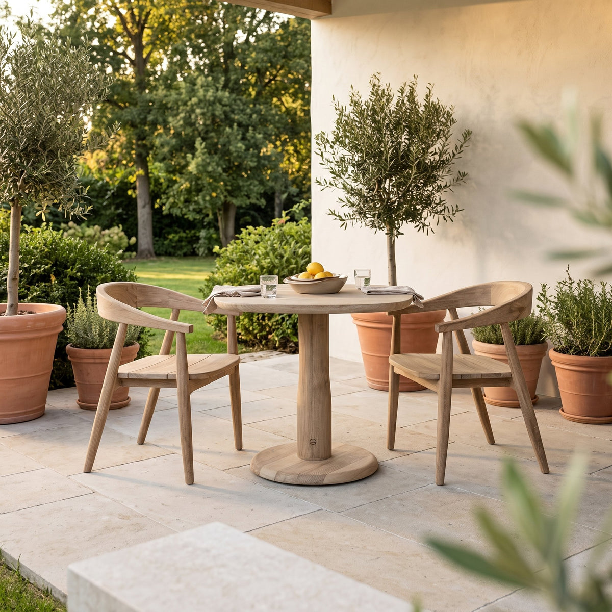 Bistrotisch Dita Squircle Teak Natural Grey von Gommaire, Teak Natural Grey, Ø 80 × H 76 cm, mit Armlehnstühlen Faye und Schale Ali auf der Gartenterrasse