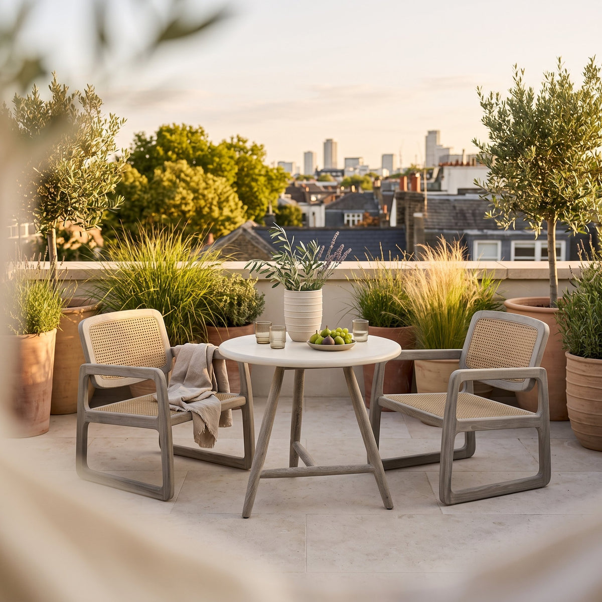 Bistrotisch Faye rund Beton Teak Natural Grey Low von Gommaire, Beton und Teak Natural Grey, Ø 75 × H 69 cm, Ambiente mit Loungesesseln Sally Open Weave und Vase Simon auf der Dachterrasse