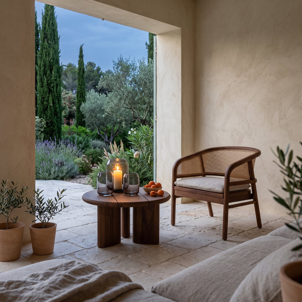Couchtisch Imen rund Teak Emas Brown Small von Gommaire, Teak Emas Brown, Ø 65 × H 35 cm, neben einem Outdoor Sessel Imen mit Windlicht Daniel in der Loggia