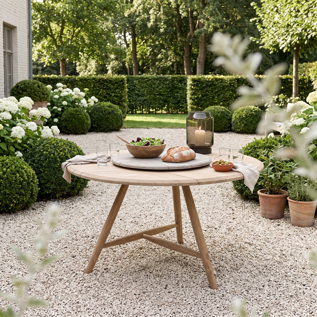 Drehteller Lazy Faye Teak Natural Grey von Gommaire, Teak Natural Grey, Ø 70 × H 3,5 cm, Interiorbild mit Esstisch Faye rund und Windlicht Daniel im Kiesgarten