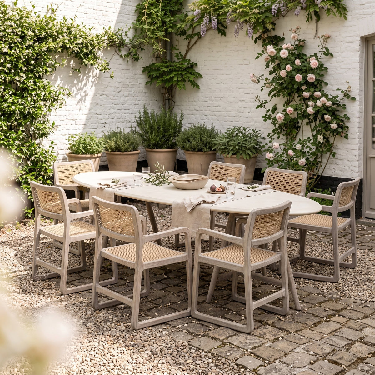 Esstisch Faye oval Beton Teak Natural Grey von Gommaire, Beton und Teak Natural Grey, 250 × 105 × H 76 cm, Ambiente mit Armlehnstühlen Sally Open Weave und Schale Ali im Innenhof