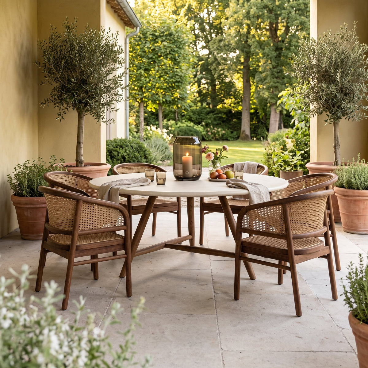 Esstisch Faye rund Beton Teak Emas Brown XL Low von Gommaire, Beton und Teak Emas Brown, Ø 170 × H 69 cm, Interiorbild mit Outdoor Sesseln Imen und Windlicht Daniel auf der Gartenterrasse