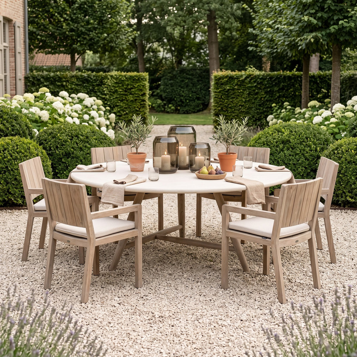 Esstisch Faye rund Beton Teak Natural Grey XL von Gommaire, Beton und Teak Natural Grey, Ø 170 × H 76 cm, Ambiente mit Armlehnenstühlen Mario und Windlicht Daniel im Kiesgarten
