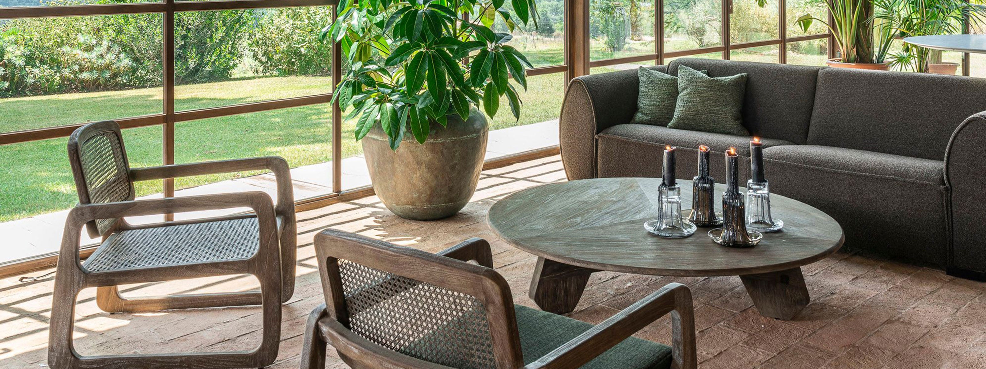 Elegante Gommaire Indoor Lounge mit Teakholz-Sesseln, Sofa und rundem Couchtisch in natürlicher Umgebung