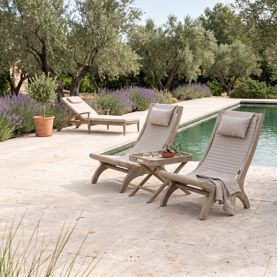 Loungesessel Beacher Sachin Teak Natural Grey Brushed Oak von Gommaire, Teak Natural Grey, Bespannung Sunbrella Brushed Oak, B 60 × T 97 × H 97,5 cm, zwei Sessel mit Tabletttisch James Small, dahinter Sonnenliege Faye am Pool