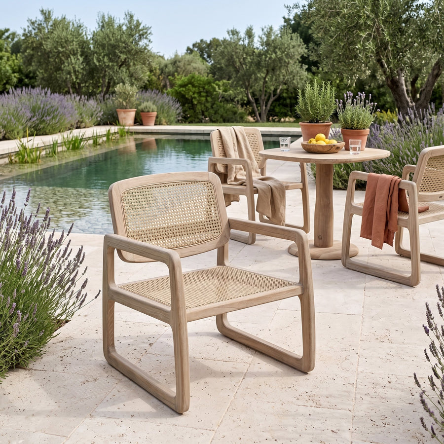 Loungesessel Sally Open Weave Teak Natural Grey von Gommaire, Teak Natural Grey und PE-Rattan, B 67 × T 75 × H 78,5 cm, im Vordergrund, dahinter Armlehnstühle Sally am Bistrotisch Dita am Pool