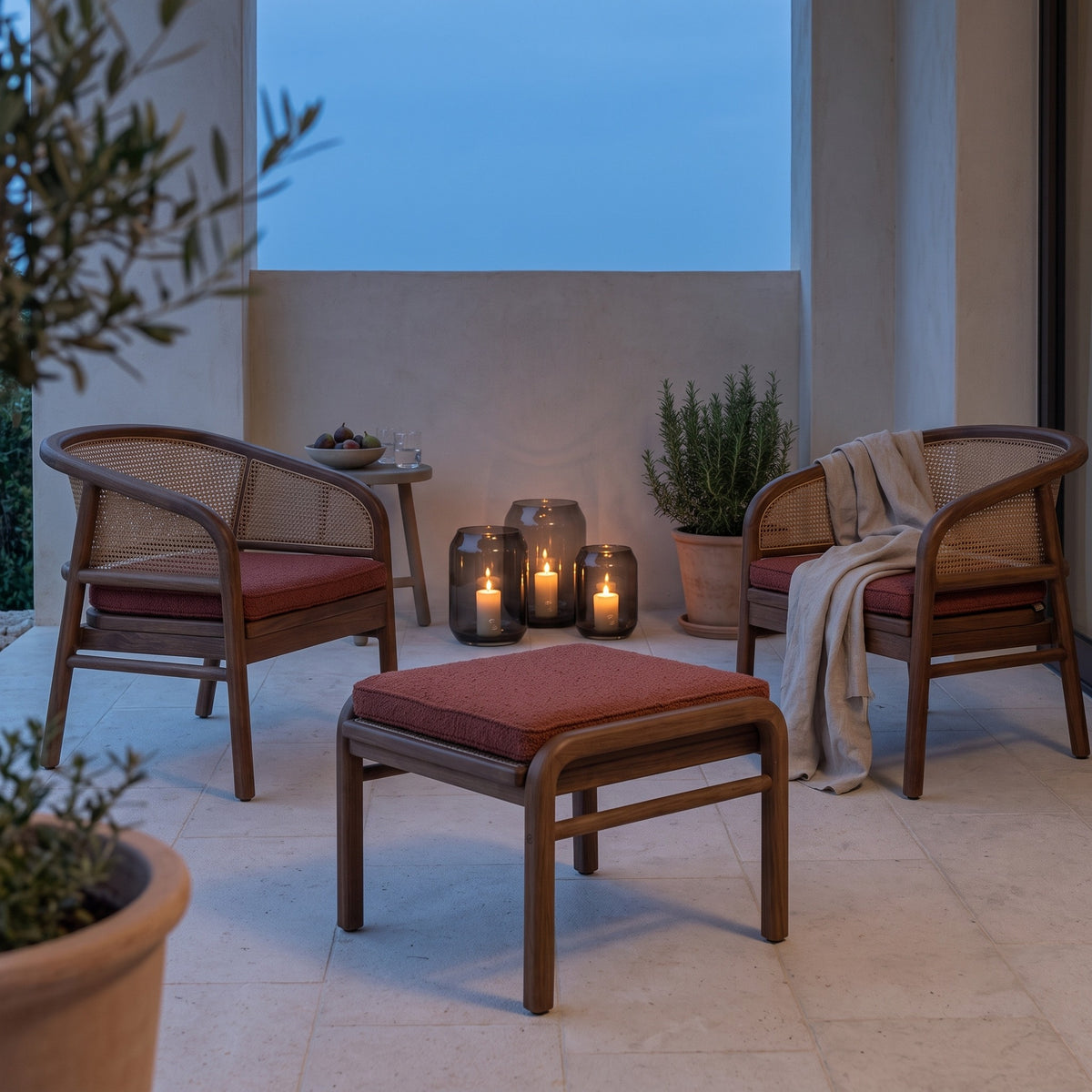 Ottomane Imen Teak Emas Brown PE Rattan von Gommaire mit zwei Sesseln Imen Teak Emas Brown und Windlicht Daniel Rauchglas in der Loggia am Abend