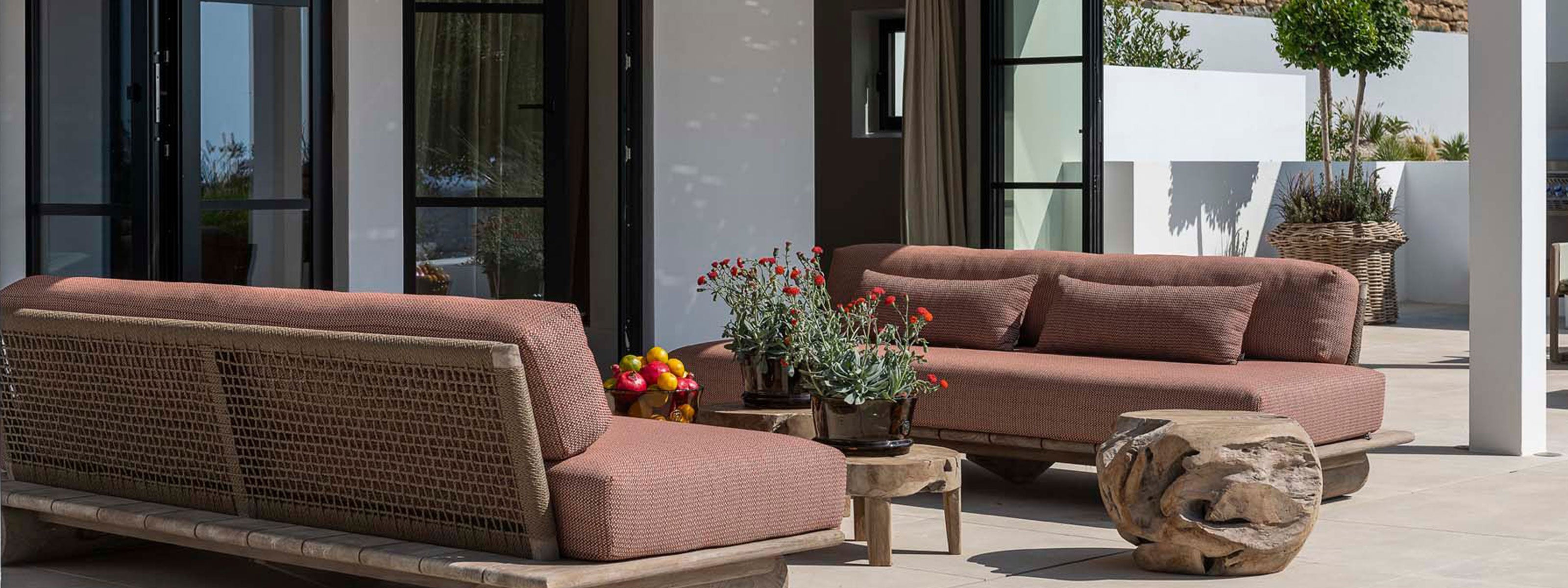 Gommaire Outdoor Sofa Edge mit Rattan-Rückenlehne, Holzbasis und hochwertigen Outdoor-Polstern auf moderner Terrasse