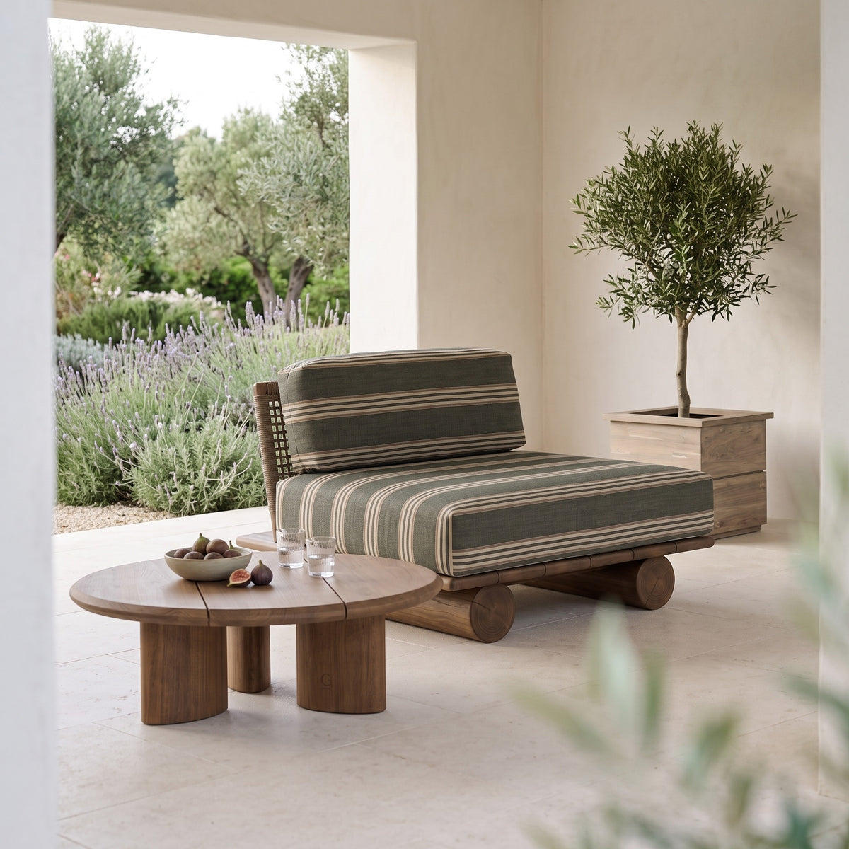 Sessel Edge Teak Emas Brown von Gommaire mit Couchtisch Imen rund Teak Emas Brown Large und Pflanzkübel Ferdy in der Loggia