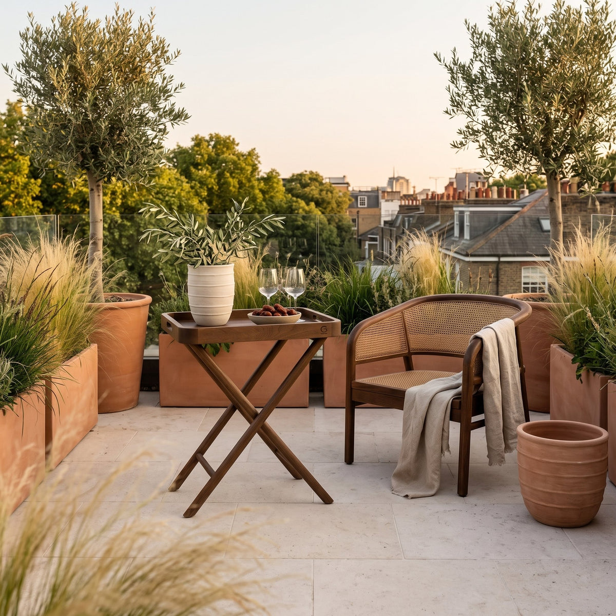Tabletttisch James Teak Emas Brown Large von Gommaire, Teak Emas Brown, 65 × 45 × H 80 cm, neben einem Outdoor Sessel Imen mit Vase Simon auf der Dachterrasse