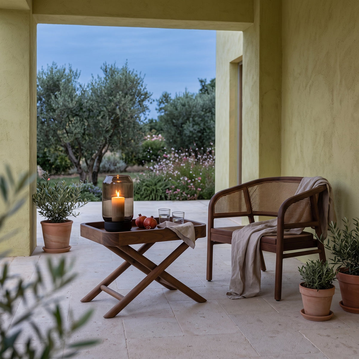 Tabletttisch James Teak Emas Brown Small von Gommaire, Teak Emas Brown, 55 × 35 × H 40 cm, neben einem Outdoor Sessel Imen mit Windlicht Daniel in der Loggia