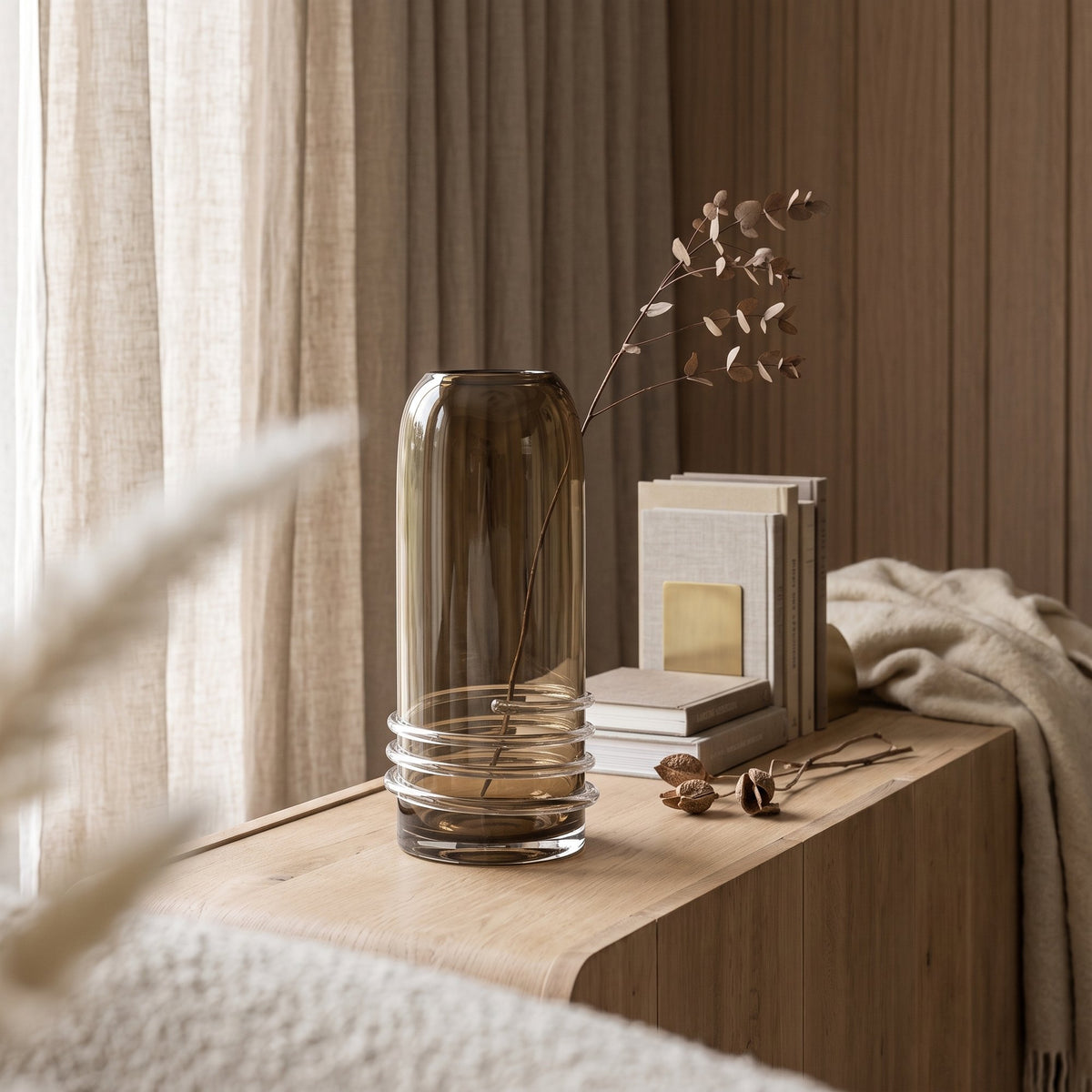 Vase Eljiot Topasglas Small von Gommaire, Glas, topasfarben getönt, Ø 13,5 × H 34 cm, Nahaufnahme im Schlafzimmer, auf dem Sideboard Vincent